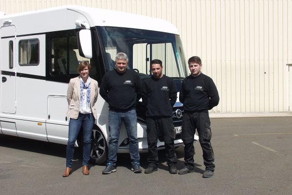 Geschäftsführerin und drei ihrer Mitarbeiter stehen vor einem weißen Wohnmobil