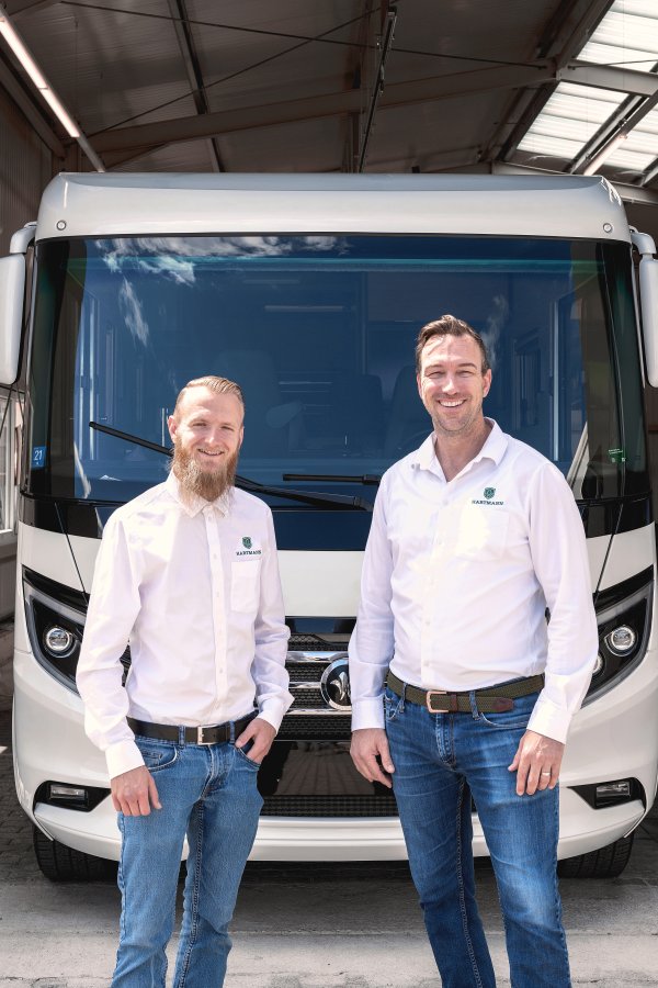 Mann mit Atemschutzmaske trägt per Hand eine Keramikversiegelung auf ein Luxuswohnmobil auf