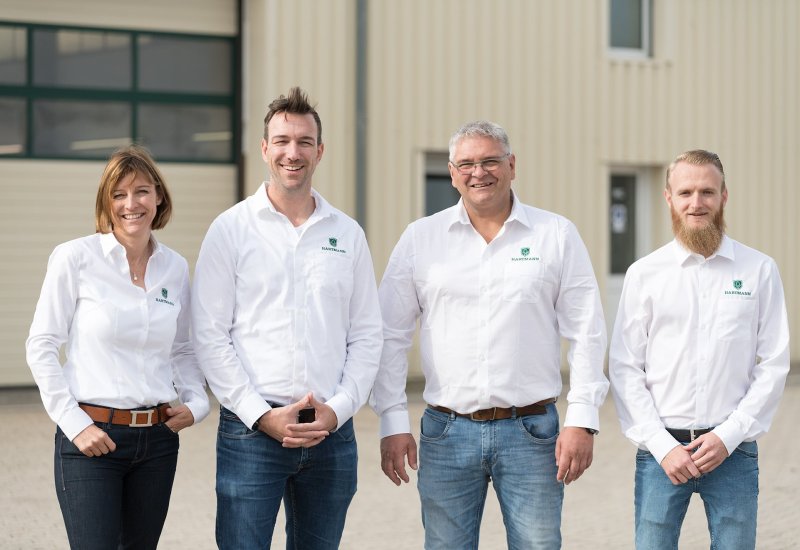 Geschäftsführerin, Geschäftsführer und Verkaufsleiter stehen vor einem gepflegt aussehenden Wohnmobil