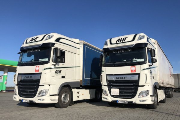 Zwi weiße LKWs die neben einer Tankstelle stehen