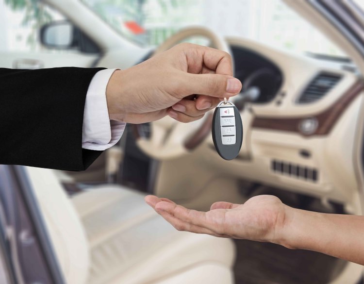 Autoschlüssel wird von einem glücklich aussehenden Mann an jemanden übergeben.