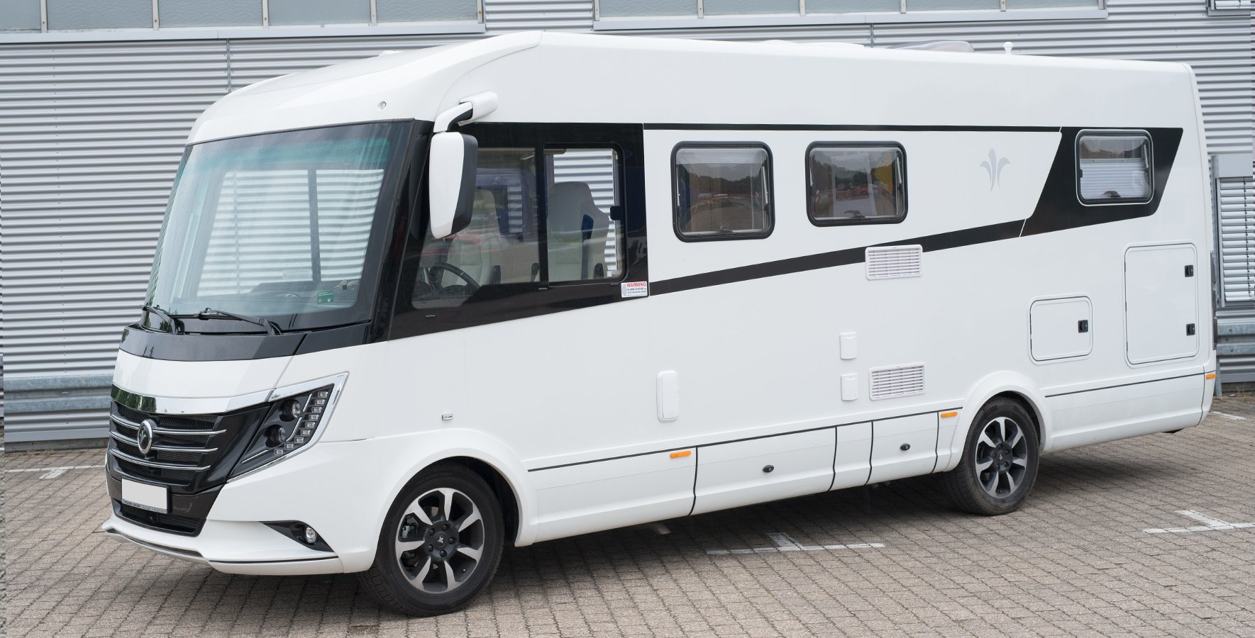schmutziger Caravan vor einer Lagerhalle 