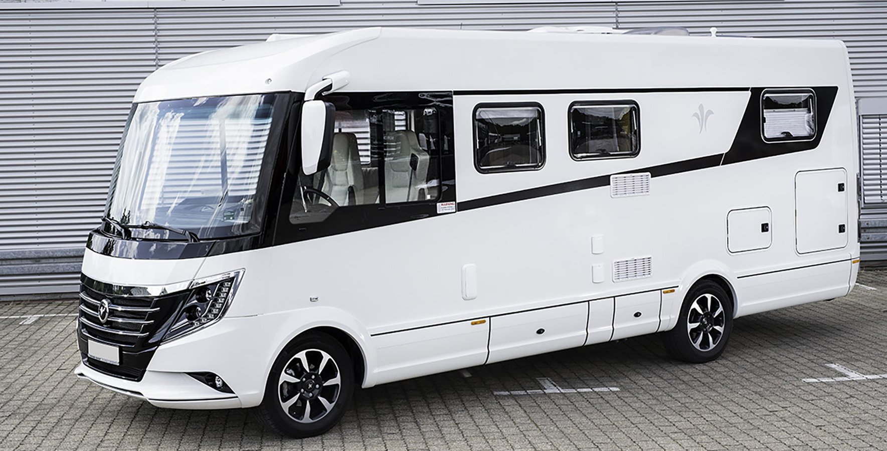 veredelter Caravan mit glänzendem Lack vor einer Lagerhalle.